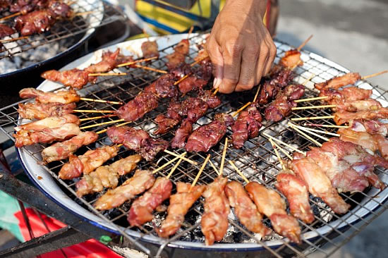 Thai street vendor barbequing satay sticks