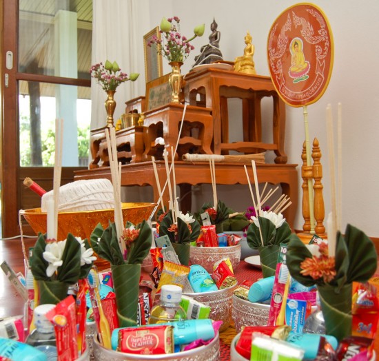 Gifts for monks in front of a Buddha image entwined with holy thread