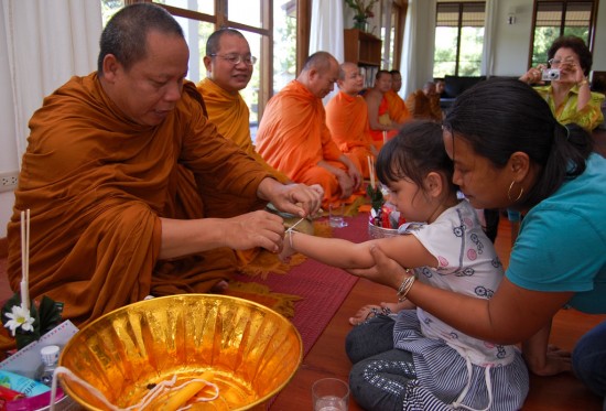 A Thai monk ties white thread around the wrist as blessing
